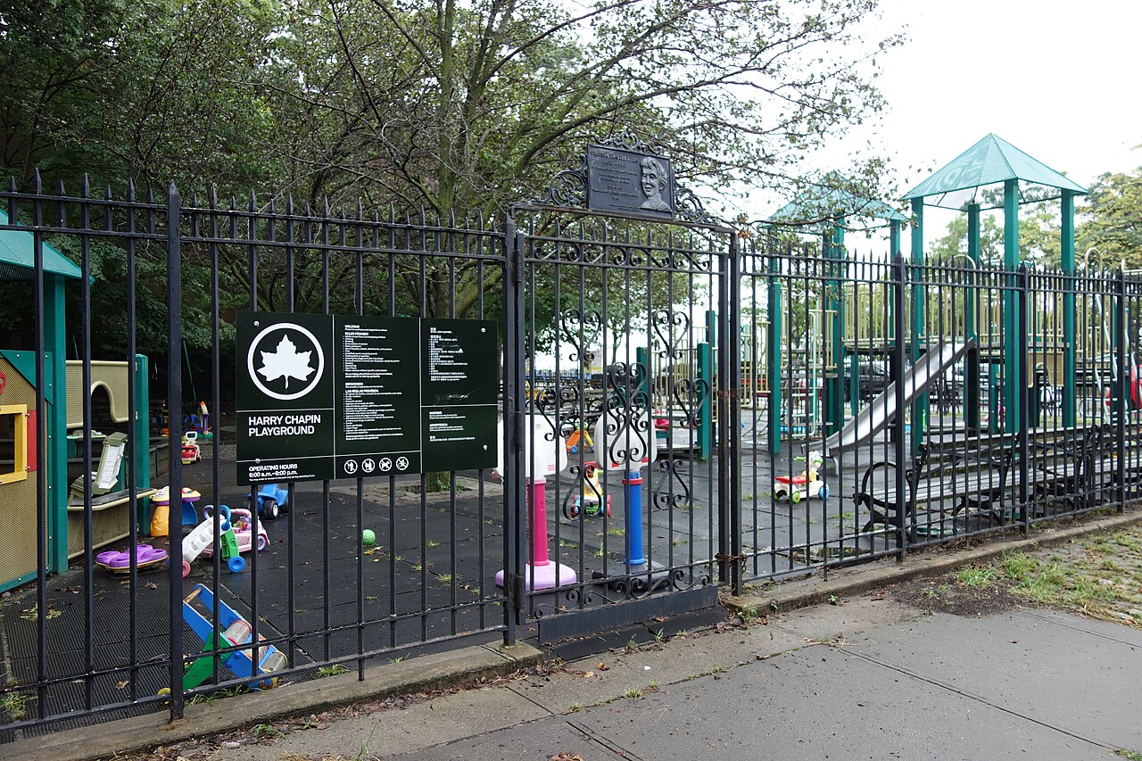 A modern NYC Parks sign outside Harry Chapin Playground, across from the Brooklyn Heights Promenade at Columbia Heights and Middagh Street in Brooklyn Heights, Brooklyn. Note that toys have been left 
